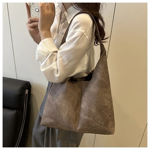 Side view of dark coffee tote bag with matte texture on model in white shirt