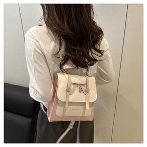 Détail d'un sac à dos patchwork rose et beige avec un nœud et un pendentif cœur sur modèle