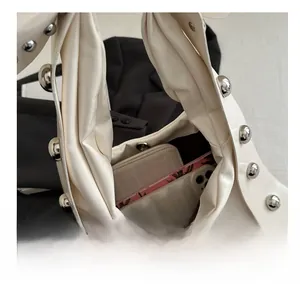 Top view of cream rivet handbag showing spacious interior with wallet and smartphone