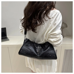 Détail du sac en cuir noir texturé avec motifs de croix gothiques et rivets argentés