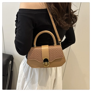 Detailed view of camel leather crossbody bag with woven texture and gold twist lock clasp