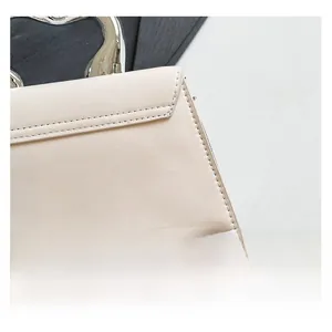 Detail of cream leather handbag showing metal handle and precise stitching accents