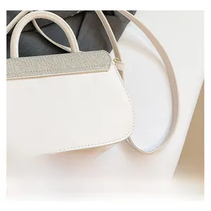 Detail shot of the white leather handbag featuring a shimmering silver sequined cover flap