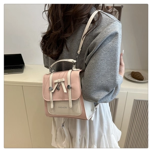 Detail of pink and cream contrast backpack with ribbon bow and heart charm on a model