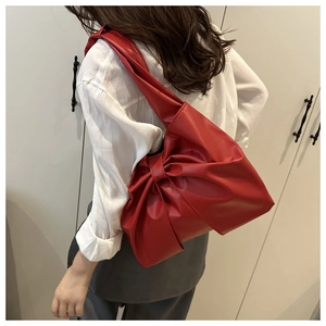 Mannequin portant un sac à bandoulière rouge avec grand nœud plissé en similicuir chic