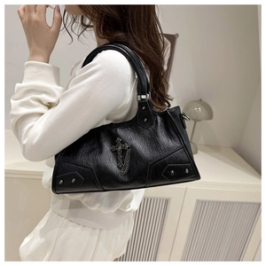 Détail du sac gothique noir avec croix argentée, chaîne et texture de cuir plissé élégant