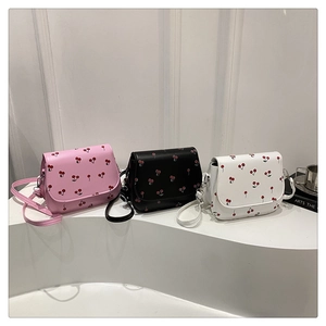 Detailed view of saddle crossbody bags with cherry prints in pink, black, and white