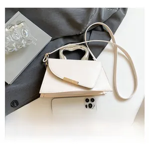 Detailed view of cream irregular handbag with unique silver fluid-shaped metal handle and strap