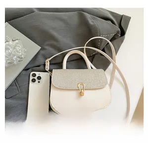 Size reference of cream mini crossbody bag showing interior capacity with a smartphone
