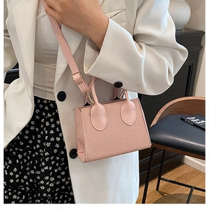 Détail du petit sac rose poudré avec texture tressée et boucles dorées sur modèle