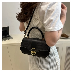 Detail of black leather and woven texture handbag with golden ring lock and hardware
