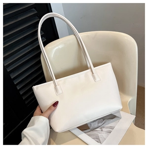 Detail view of white minimalist tote bag with matte leather texture on a beige chair