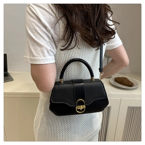 Detail of a black woven leather tote bag with gold metal clasp on a female model