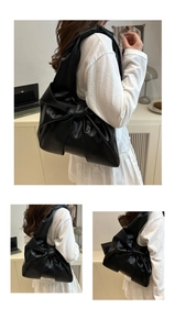 Detail of black bow shoulder bag with glossy PU leather finish and stylish wide strap