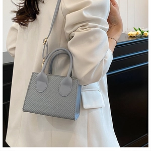 Détail du sac bandoulière bleu clair avec texture tissée et boucle en métal doré