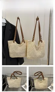 Dettaglio della borsa tote intrecciata beige con manici in ecopelle marrone e borchie