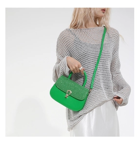 Detail of bright green leather bag with shimmering sequined flap and gold lock hardware