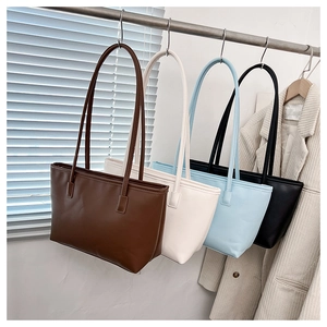 Detail view of large tote bags in coffee, cream, sky blue and black hanging by straps