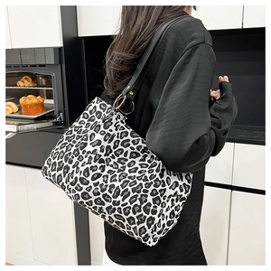 Detail of leopard print tote bag with black faux leather strap and gold metal rings