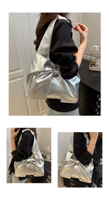 Close-up of a silver metallic tote bag featuring a large decorative bow design