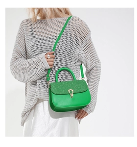 Green sequined handbag with gold clasp worn as a crossbody bag by a female model