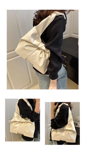 Close-up of a large cream bow-shaped tote bag showing smooth faux leather texture and detail