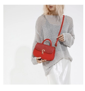 Detail of red glitter flap and golden horseshoe buckle on stylish crossbody bag