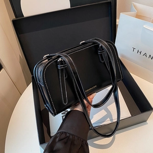 Minimalist black faux leather shoulder bag with white contrast stitching and long handles