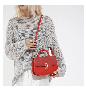 Model wearing a red leather crossbody bag with glitter flap and gold V-shaped hardware