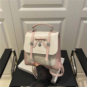 Mini zaino rosa e bianco con fiocco e ciondolo a cuore appoggiato su una sedia
