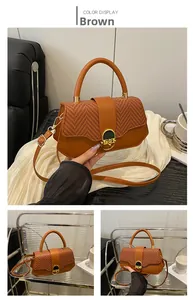 Detail of brown box bag featuring woven texture flap and golden twist lock closure