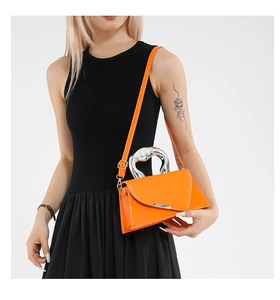 Detail of bright orange envelope bag with unique silver fluid-shaped metal handle