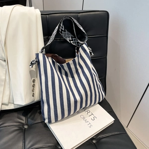 Blau-weiß gestreifte Canvas-Tragetasche mit geometrischem Jacquard-Gurt auf Stuhl