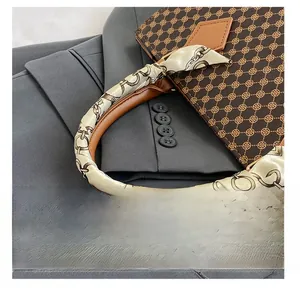 Detail of leather handle with silk scarf wrap on brown monogram satchel bag
