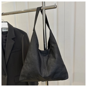 Detail of a black minimalist tote bag with matte texture and wide shoulder strap