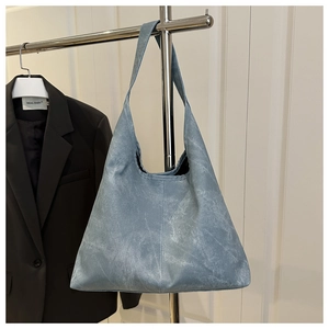 Detailed view of light blue tote bag with unique washed texture and wide shoulder strap