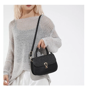 Close-up of black faux leather crossbody bag with sparkling flap and gold metal buckle