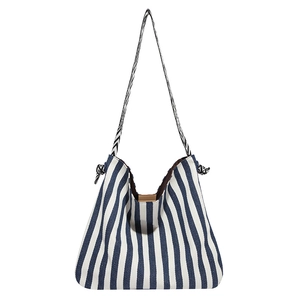 Blue and white striped canvas shoulder bag with geometric patterned strap on white background