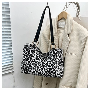Detail view of leopard print tote bag with black leather straps and gold rings on a hanger