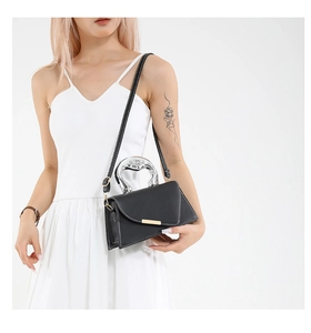 Detail of black leather handbag with white contrast stitching and silver metal handle
