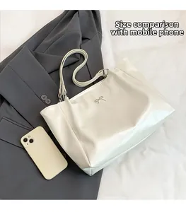 Macro shot of a white PU leather tote bag showing spacious interior and metallic bow detail