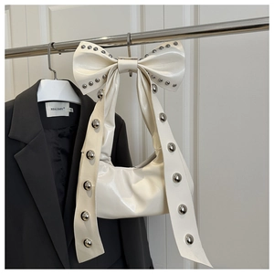 Dettaglio di una borsa a fiocco bianco crema con rivetti in metallo argento su pelle PU lucida