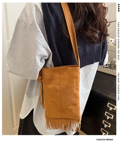 Detail of vintage brown suede crossbody bag with elegant fringe tassels for women