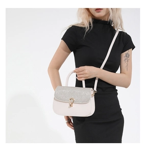 Detail of elegant beige crossbody bag featuring shimmering rhinestone flap and gold buckle