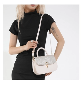 Close-up of elegant white flap bag with silver sequins and golden clasp worn by a model