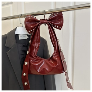 Dettaglio borsa sottobraccio rosso scuro con maxi fiocco e borchie metalliche argento