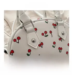 Close-up of white PU leather handbag with cherry pattern and silver metallic buckle