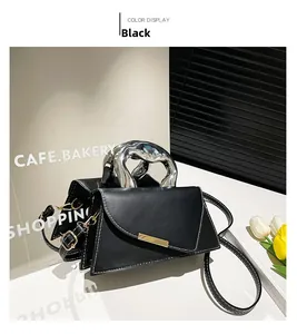 Detail of artistic silver fluid-shaped handle on black leather trapezoid handbag
