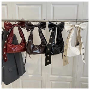 Collection of four bow-shaped underarm bags with metallic studs in various colors