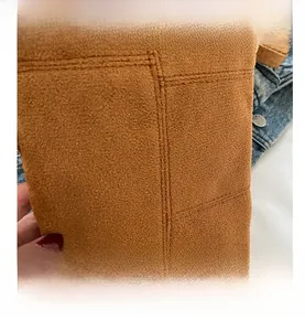 Detailed view of brown suede texture with cross-stitch and retro tassel decoration